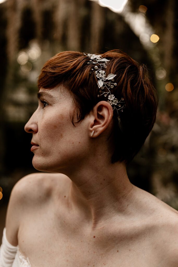 A close-up profile of a bride with short hair wearing a floral headpiece, captured in the Orchid Garden."