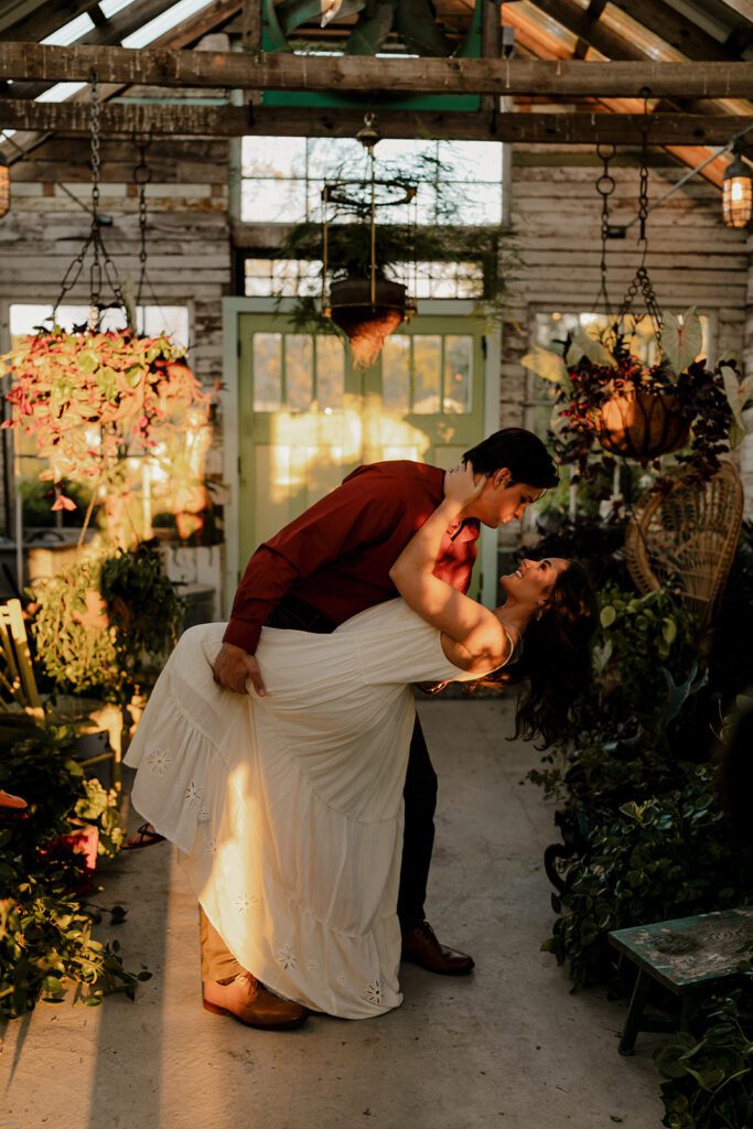 Jake and Keaton dancing in the sunlight inside the greenhouse at West Milford Farm during their engagement session."