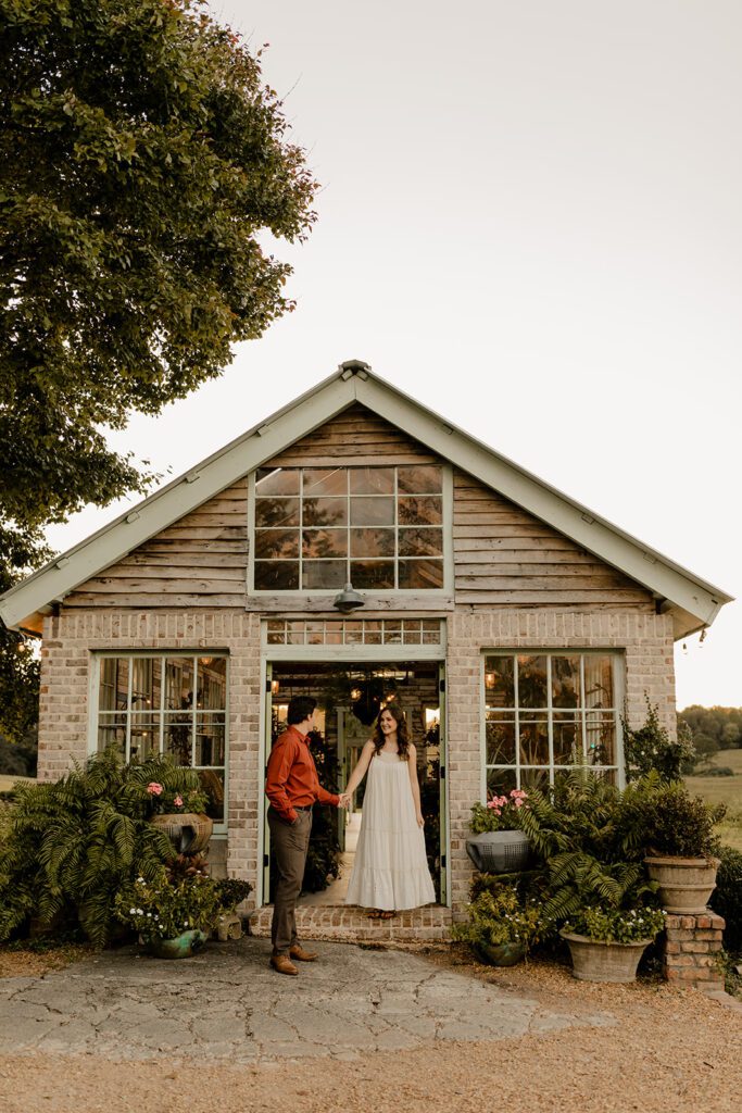 Jake and Keaton standing in front of the greenhouse at West Milford Farm during their engagement session.