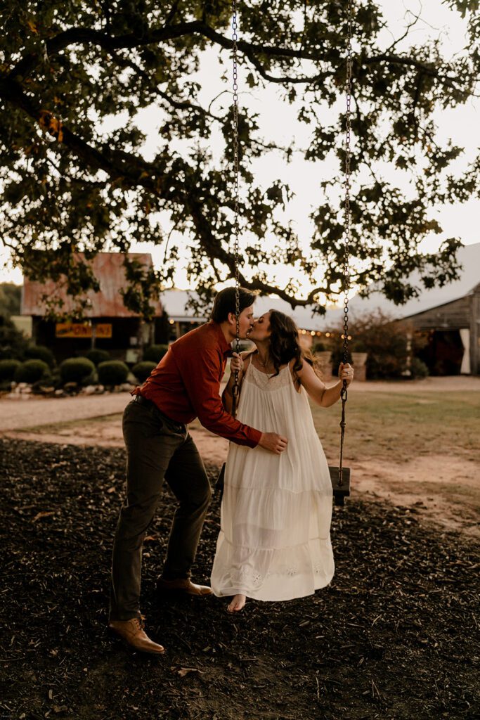 Jake and Keaton sharing a kiss by the rope swing during their engagement session at West Milford Farm.