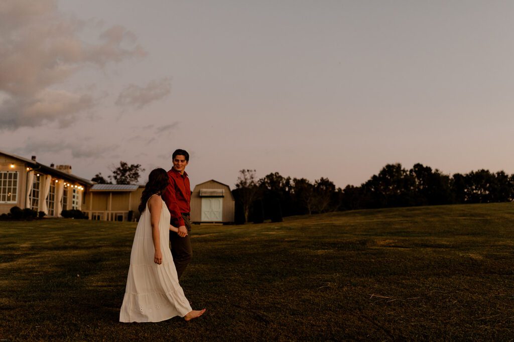 ake and Keaton walking hand in hand across the open field during sunset at West Milford Farm, enjoying the peaceful surroundings