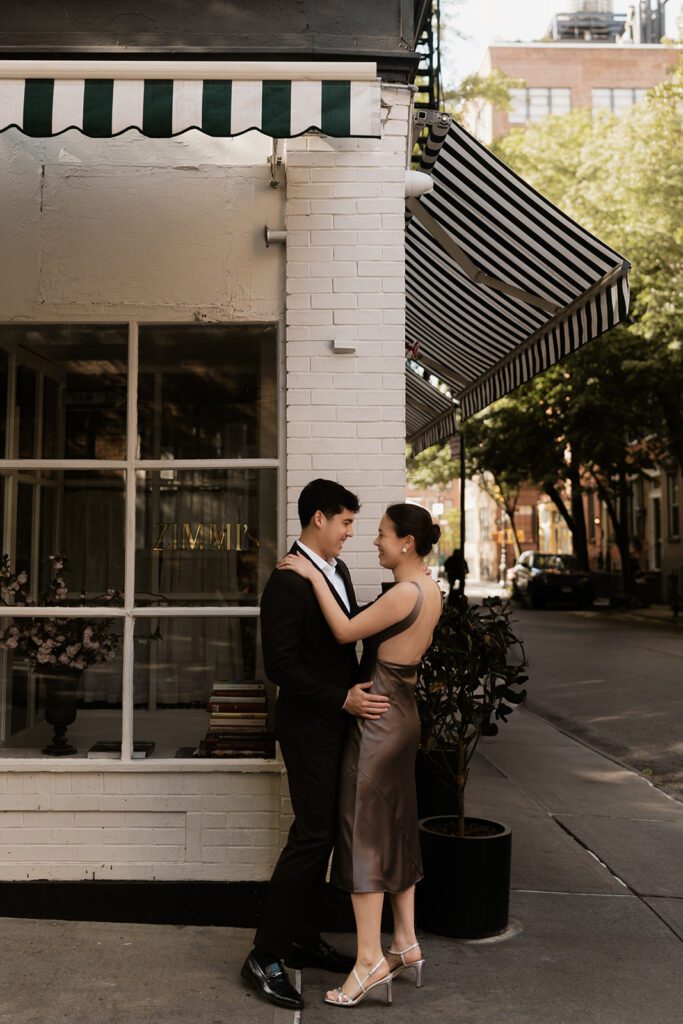 Couple embracing outside a West Village café during their NYC engagement session

