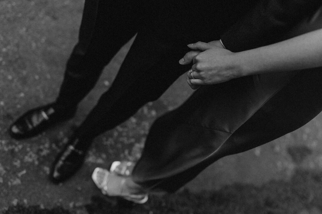Close-up black-and-white image of engaged couple holding hands during their NYC engagement session

