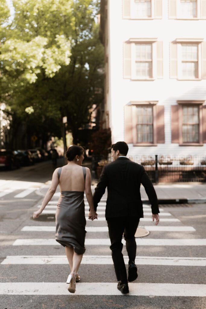 Engaged couple holding hands and crossing the street during their West Village NYC engagement photoshoot