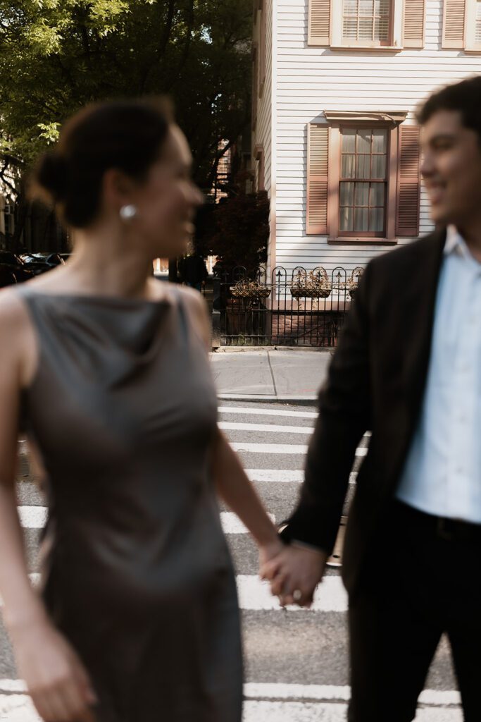 Candid moment of couple smiling and holding hands during their West Village NYC engagement session

