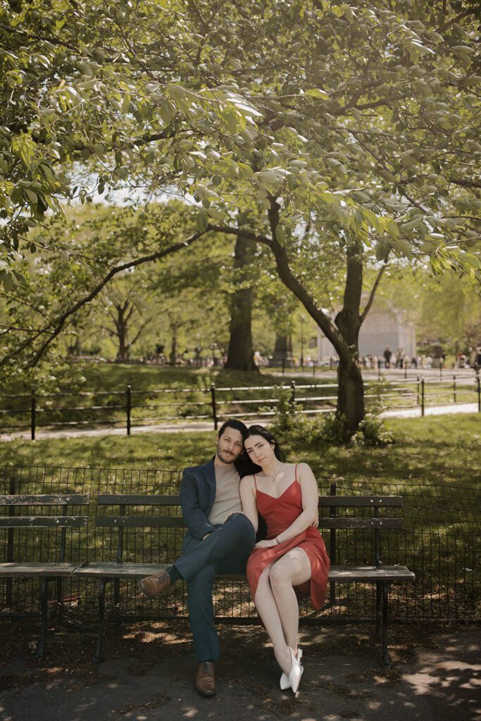 Couple sitting close on a Central Park bench under leafy trees