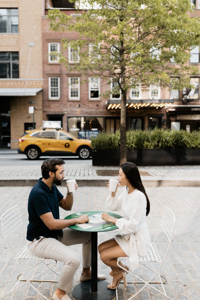 Engaged couple drinking coffee at a sidewalk café in Chelsea NYC with brick buildings and a yellow taxi in the background