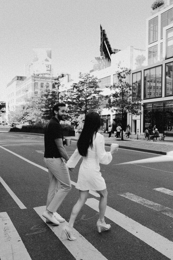 Black-and-white image of engaged couple crossing the street in Chelsea NYC during their morning session

