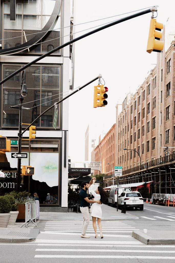 Wide shot of engaged couple dancing in the street under traffic lights in Chelsea NYC

