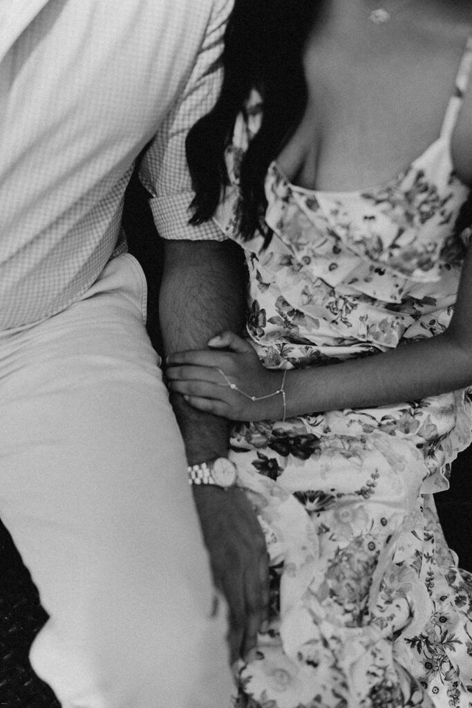 Black-and-white close-up of engaged couple’s intertwined hands and floral dress during SoHo engagement session

