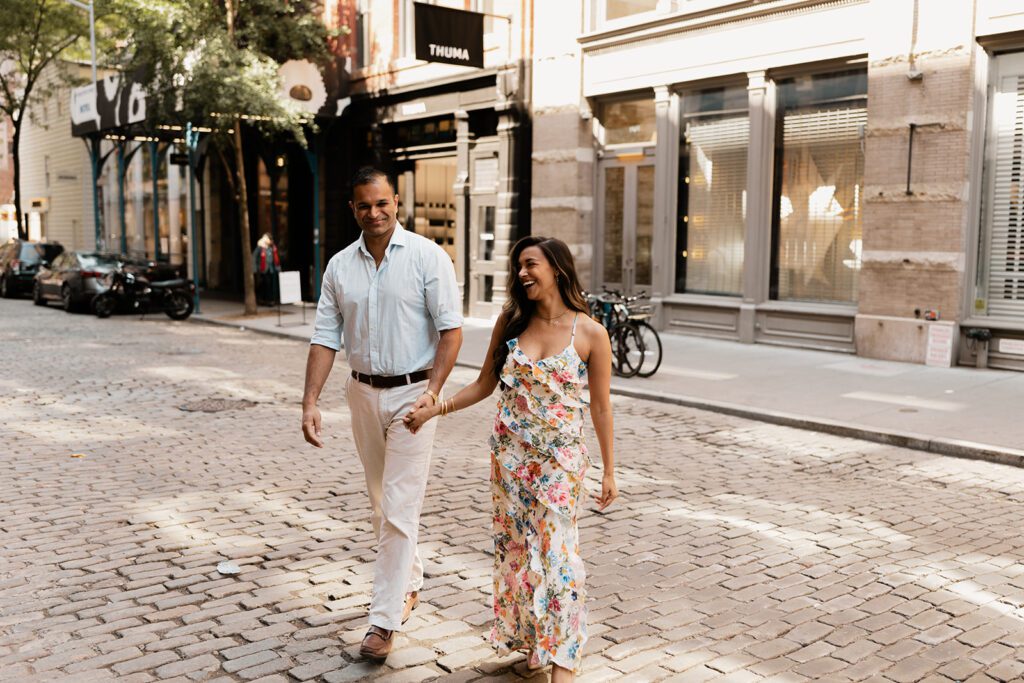 Engaged couple walking hand-in-hand and smiling during their SoHo NYC engagement session

